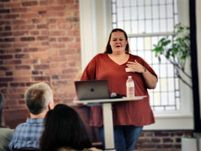photo of a women in a red shirt speaking at a public event