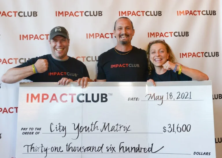 Photo of 3 smiling people holding a Impact Club check for $31,600